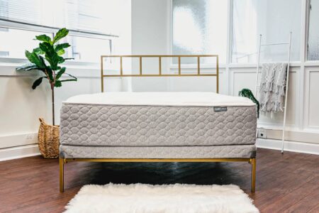 Luxurious mattress on modern bed frame in bright bedroom with natural light and cozy decor, emphasizing quality sleep and mattress options on The Mattress Underground website.