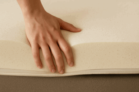 Soft latex mattress top layer with hand pressing to showcase comfort and foam quality.