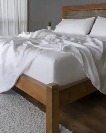 Mattress on a wooden bed frame with white bedding, highlighting sleep comfort and mattress selection.