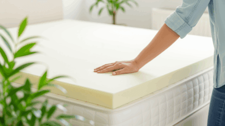 A close-up of a hand pressing into a high-quality polyurethane memory foam mattress comfort layer to test its softness, contouring, and support.