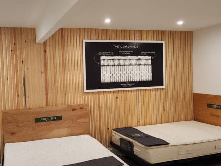 Mattress Makers showroom featuring The Coronado mattress beneath a framed cutaway diagram illustrating its internal mattress construction and layers.