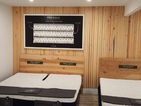 Presidio mattresses displayed in the Mattress Makers showroom beneath a framed cutaway diagram illustrating the mattress’s layered internal construction.